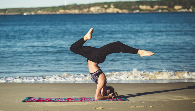 woman practicing yoga on the beach