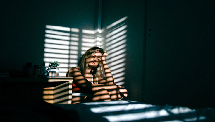 Girl is sitting on the bed and feeling tired