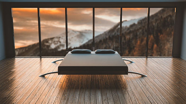 white bed with two black pillows and beautiful mountains covered with snow in the background