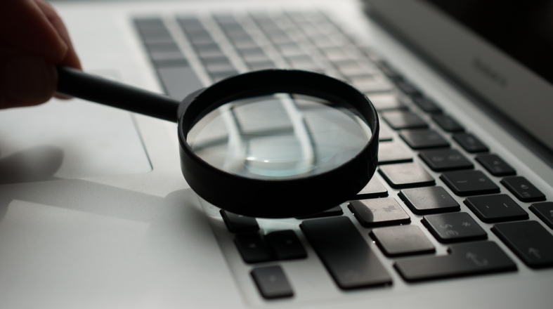 a person is holding a magnifying glass above laptop