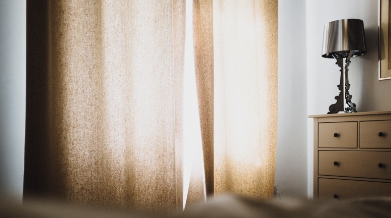 a room with beige curtains and a lamp on the small closet
