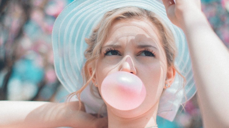 blonde woman is blowing a bubble with a gum blonde woman is blowing a bubble with a gum
