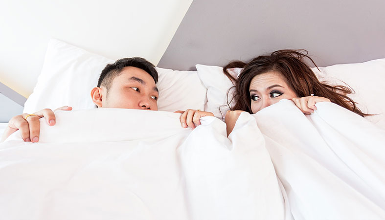 Couple is laying on the bed covered with white cover