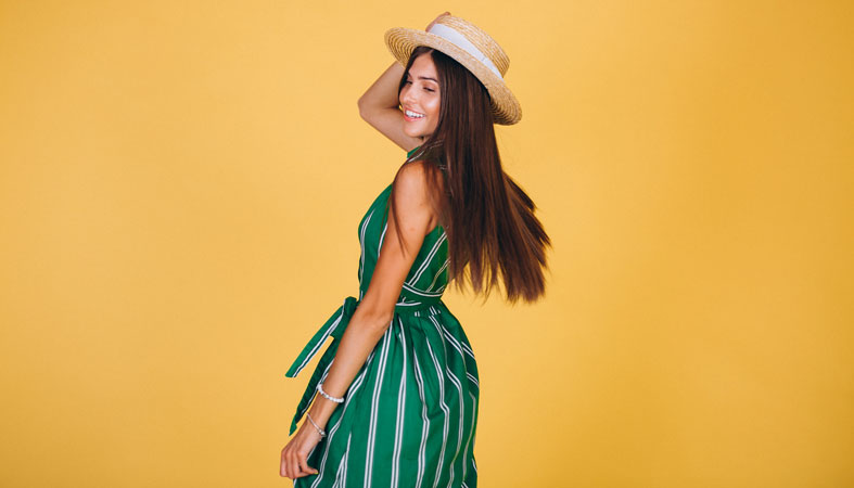 happy-woman-in-a-green-dress-with-a-hat-on-a-yellow-background happy woman in a green dress with a hat on a yellow background