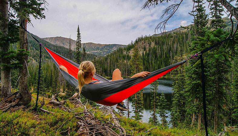 a girl is relaxing in the hammock in the nature