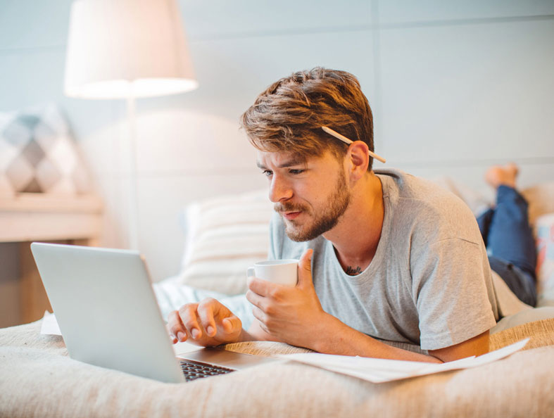 man checking email in bed