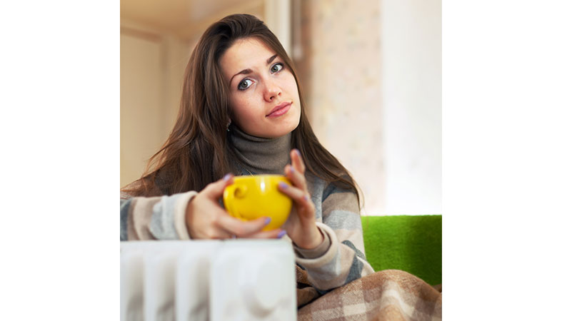 a young woman is drinking a coffee next to the radiator