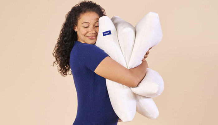 A woman is holding three Casper pillows