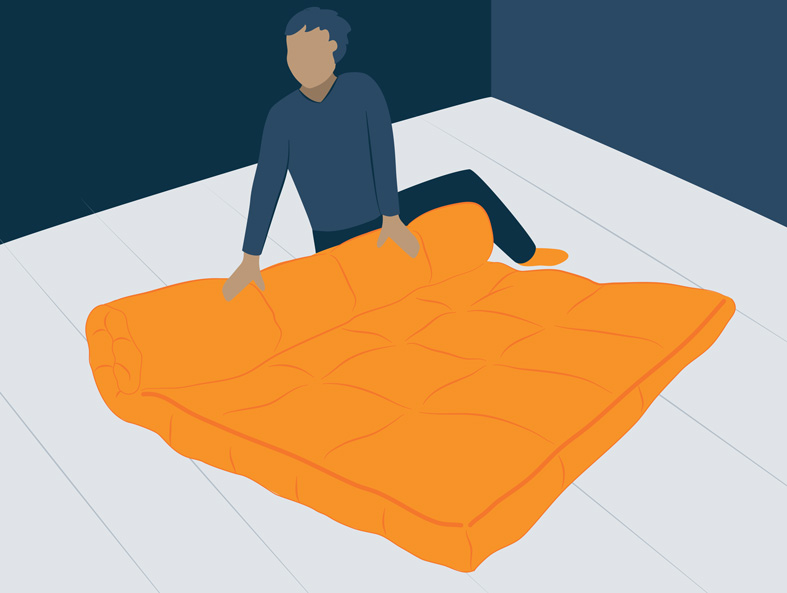 a person rolling a futon on the floor for storage
