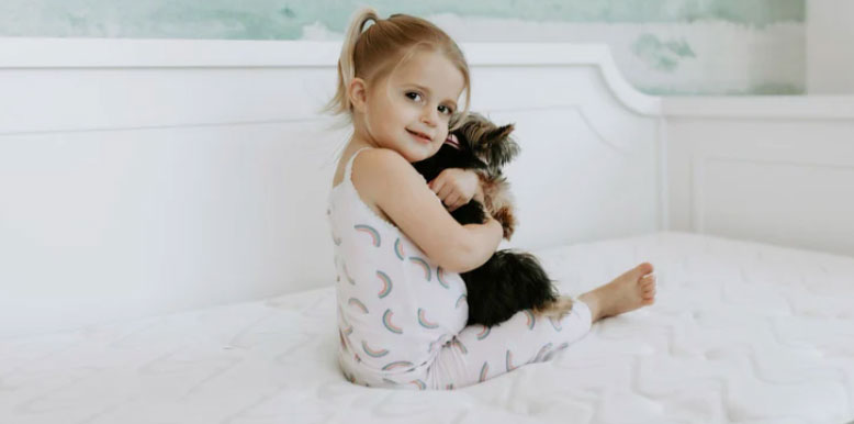 a little girl with her dog is sitting on nest puffin bed